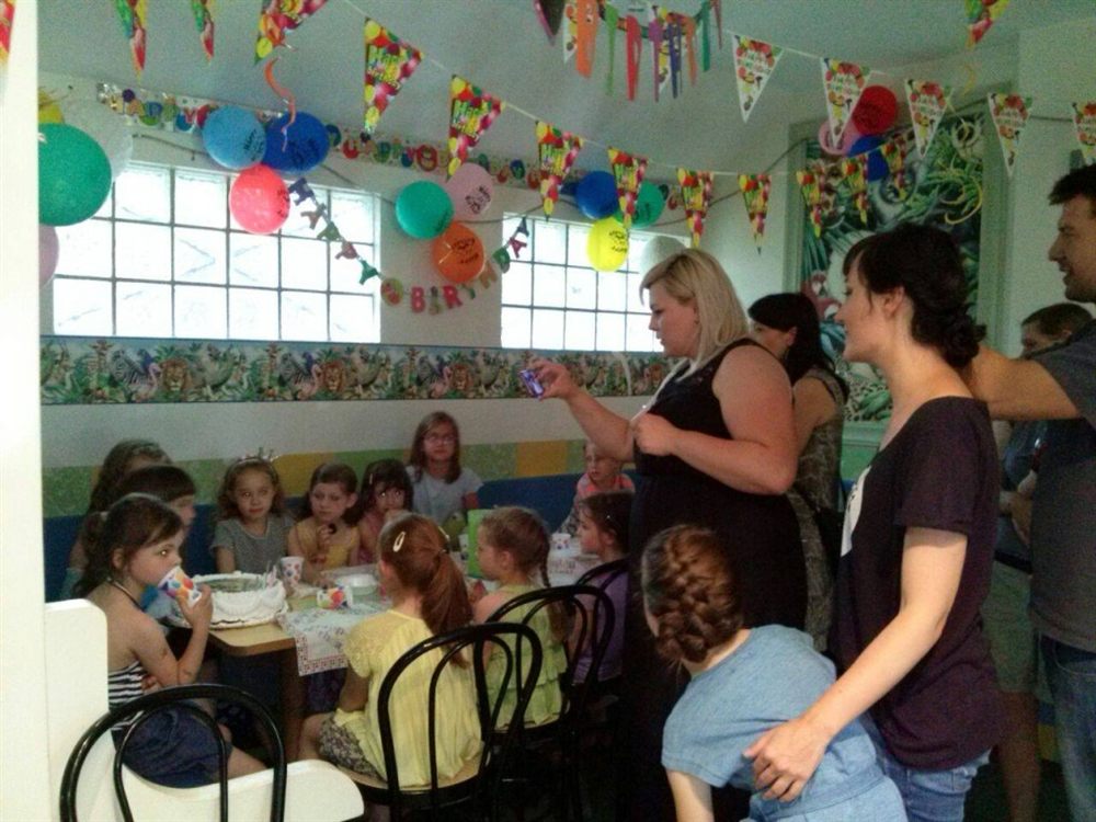 A real birthday party in Malibu's soft play room, children and parents around the tables